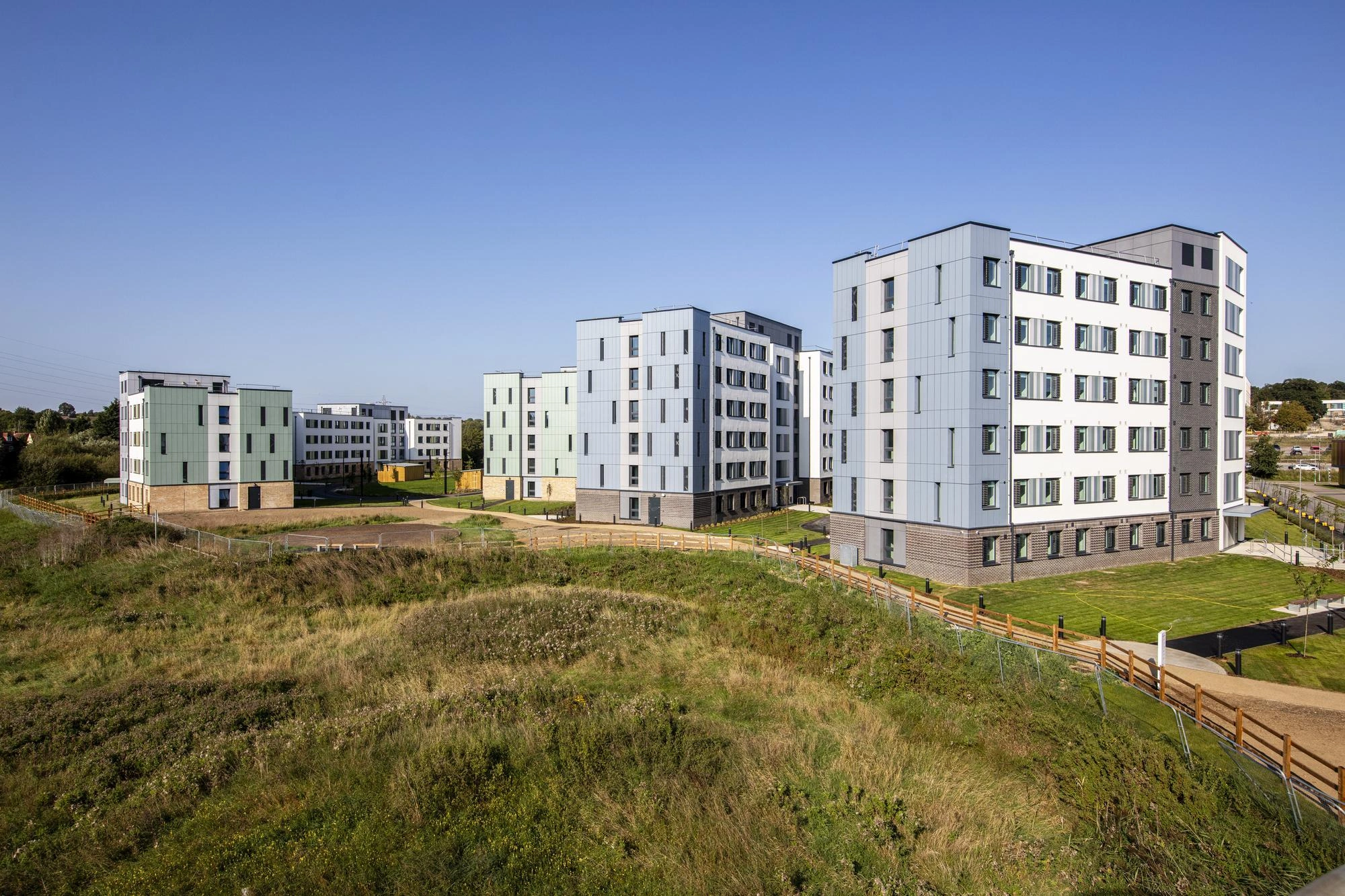 Immeubles d'appartements modernes avec des façades colorées dans un paysage verdoyant sous un ciel bleu dégagé.