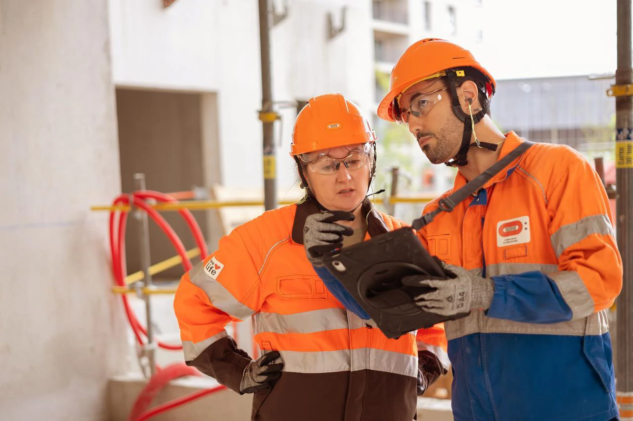 Deux ouvriers sur un chantier regardent ensemble une tablette.