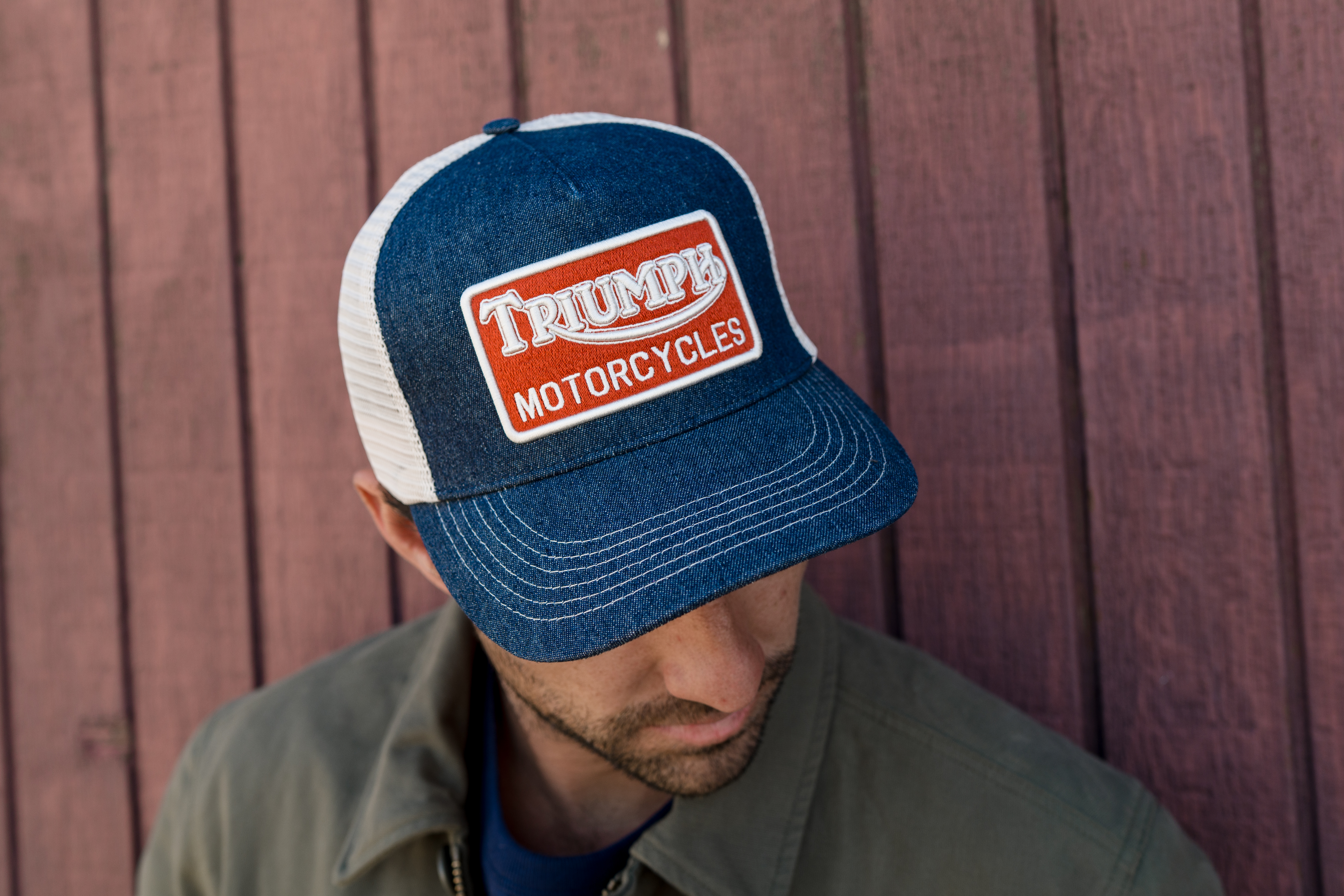 Man kneeling down wearing a Triumph Heritage Cap