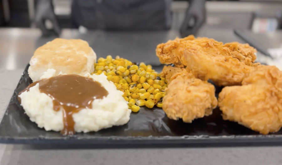 A platter of classic Southern comfort food with mashed potatoes, corn, a biscuit, and crispy, fried chicken.