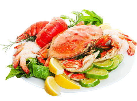 Group of seafood including shrimp, lobster, and crab with citrus and herb accoutrement.