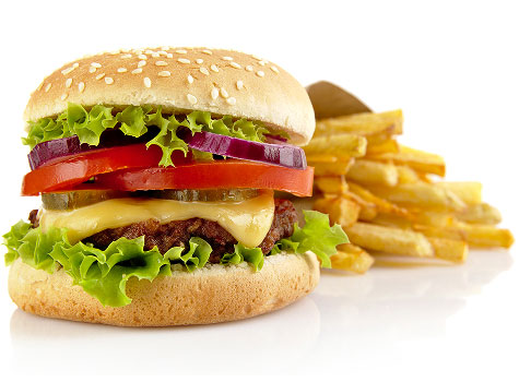 A cheeseburger with lettuce, tomatoes, onions, and pickles with a side of fries.
